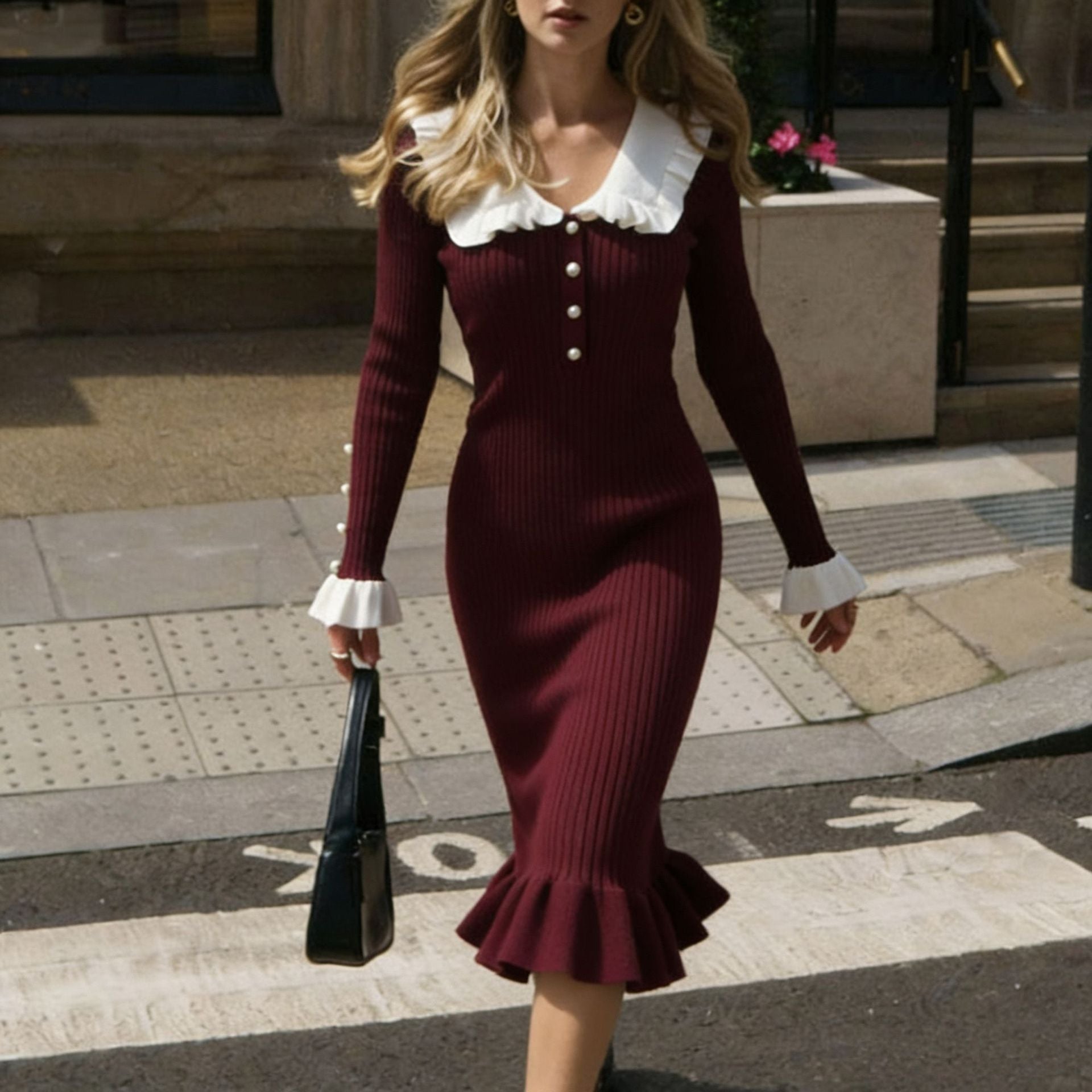 Woman wearing a burgundy dress with white ruffled collar and cuffs, walking outdoors.