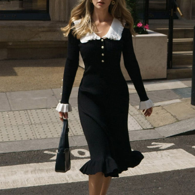 Woman in a black and white dress walking on a city street.
